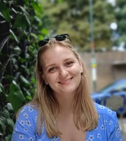 Bright young woman smiling outdoors, casual fashion, natural lighting, urban background, lifestyle image.