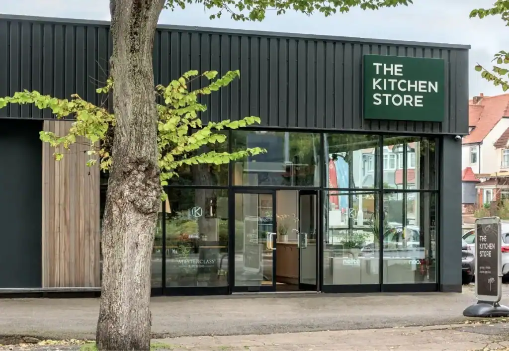 Modern kitchen store storefront with large glass windows and signage, situated in a neighbourhood.